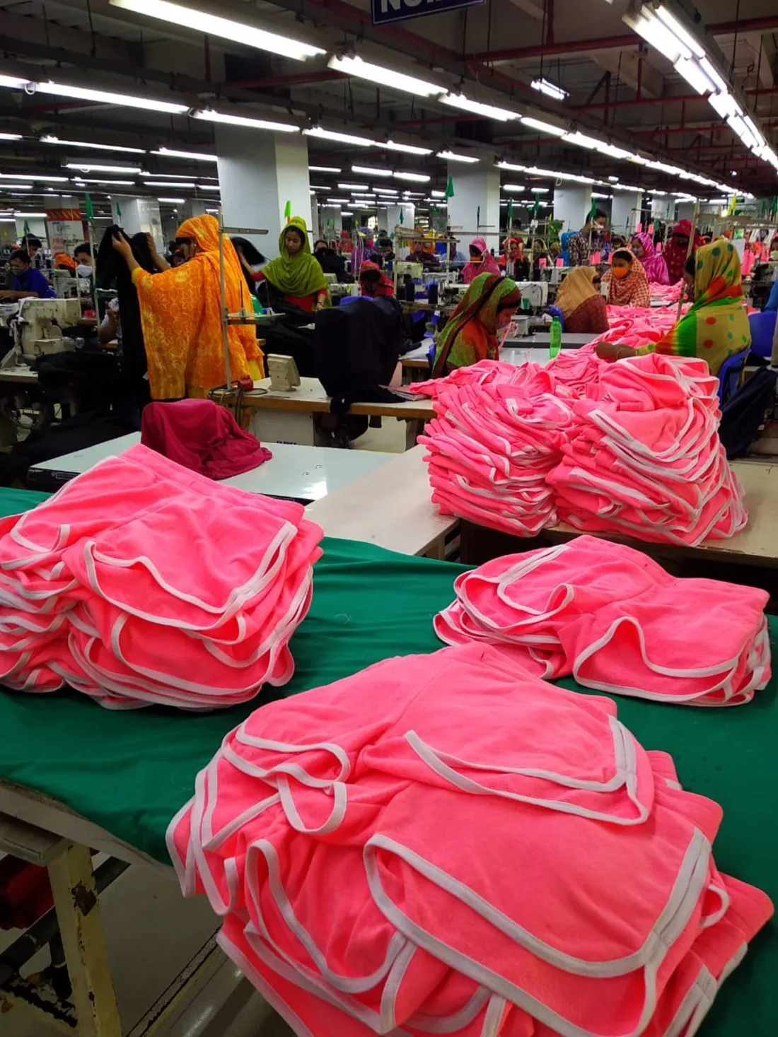 Vibrant pink garments stacked on the sewing line at our Dhaka factory